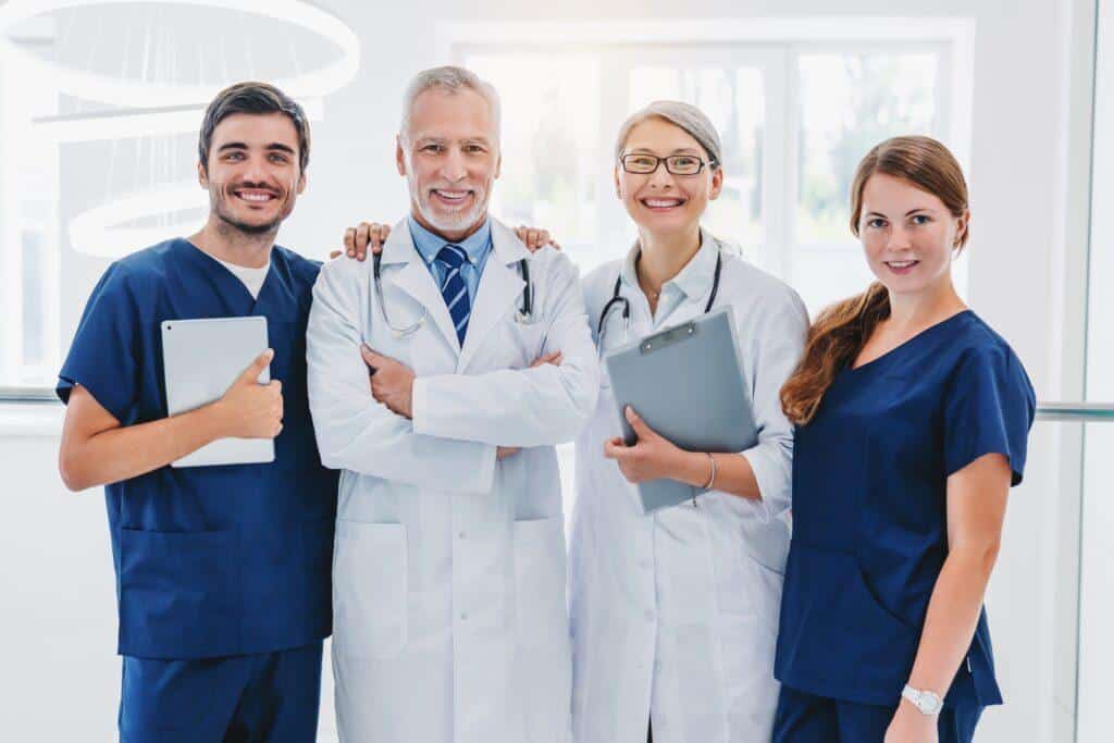 Team of medical doctors looking at camera and smiling while standing in hospital